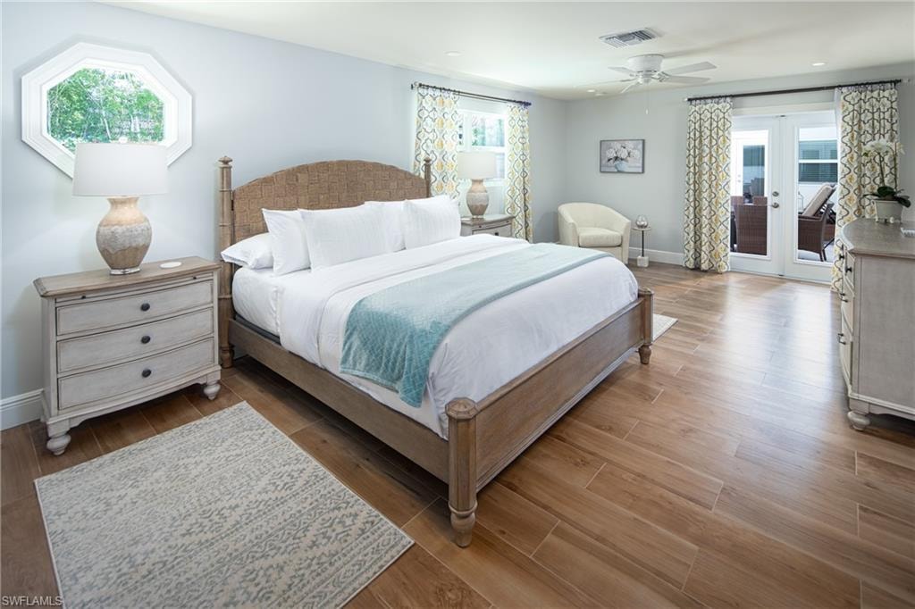 Bedroom with multiple windows, access to outside, and wood finished floors