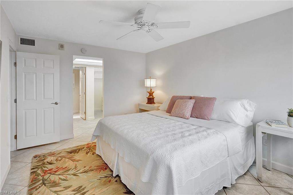 Bedroom featuring light tile patterned flooring, ensuite bath, and ceiling fan