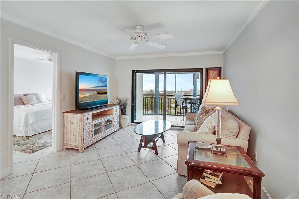 Living room with ornamental molding, light tile patterned floors, and a ceiling fan