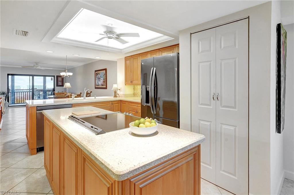 Kitchen featuring light tile patterned floors, stainless steel appliances, a peninsula, a chandelier, and a kitchen island