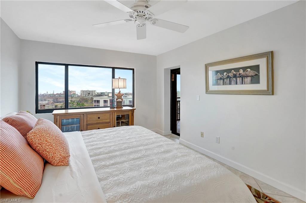 Bedroom with light tile patterned floors, a city view, and a ceiling fan
