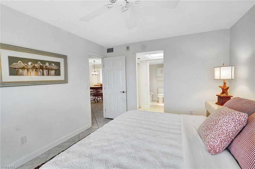 Bedroom featuring light tile patterned floors, a ceiling fan, connected bathroom, and a chandelier