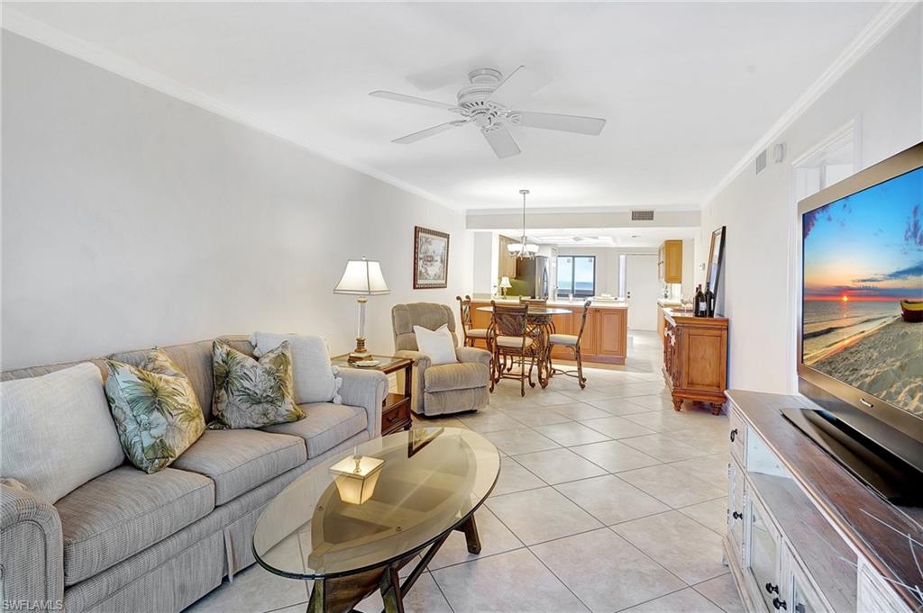 Living area featuring crown molding, light tile patterned flooring, and ceiling fan