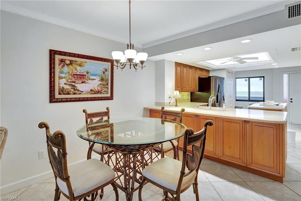 Dining area with light tile patterned floors, crown molding, recessed lighting, a chandelier, and a tray ceiling