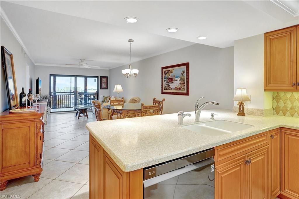 Kitchen featuring light tile patterned floors, dishwasher, pendant lighting, decorative backsplash, and light stone counters