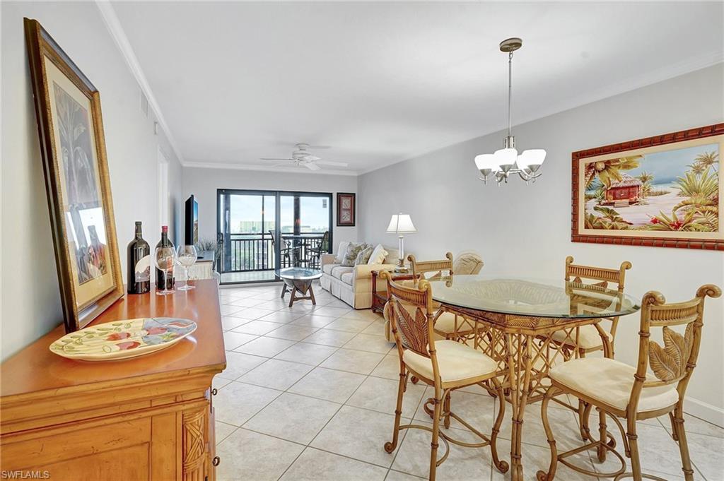 Dining space featuring ornamental molding, light tile patterned floors, a ceiling fan, and a chandelier