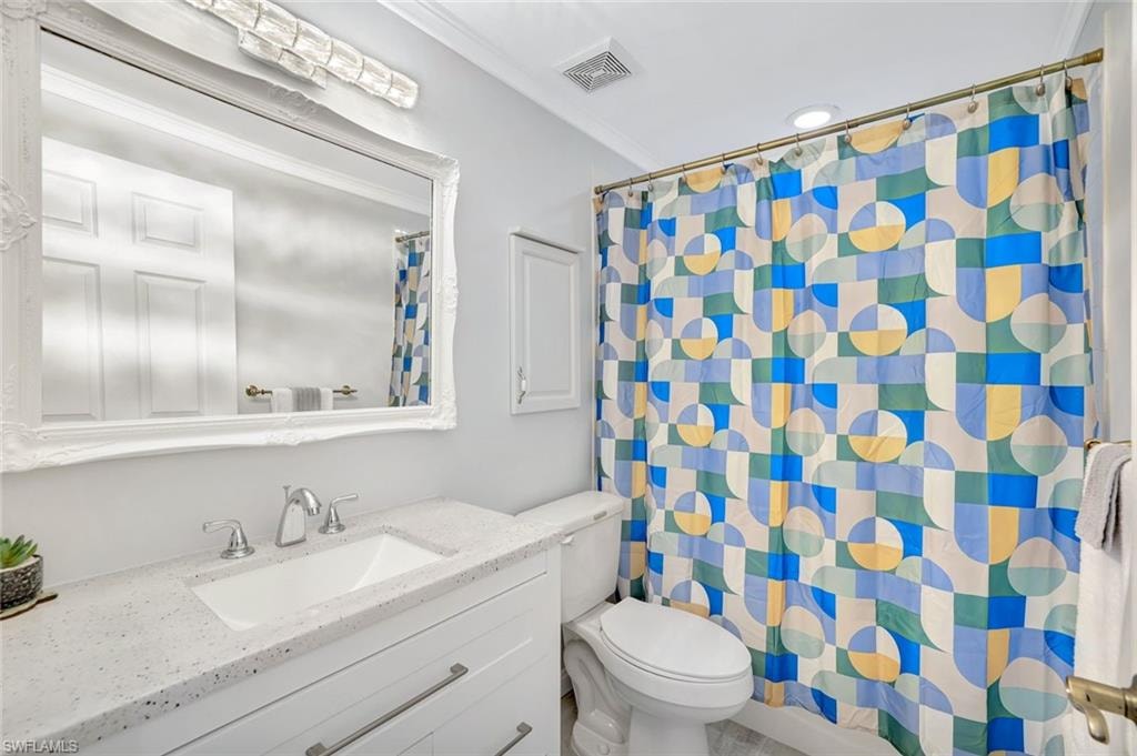 Bathroom featuring vanity, ornamental molding, and curtained shower