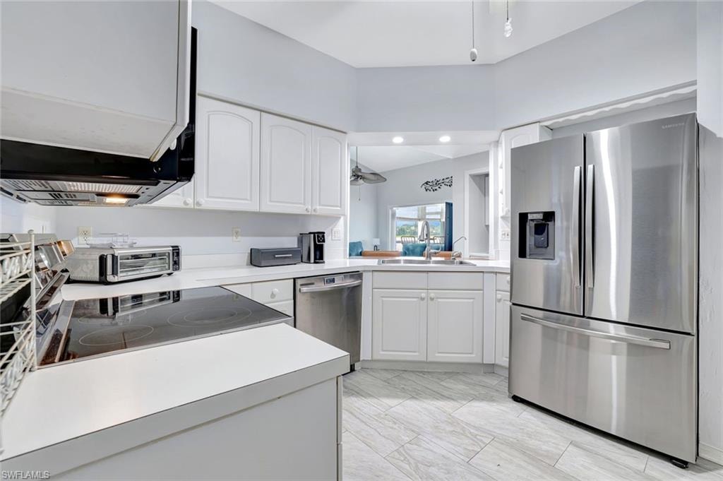 Kitchen featuring stainless steel appliances, white cabinets, and light countertops