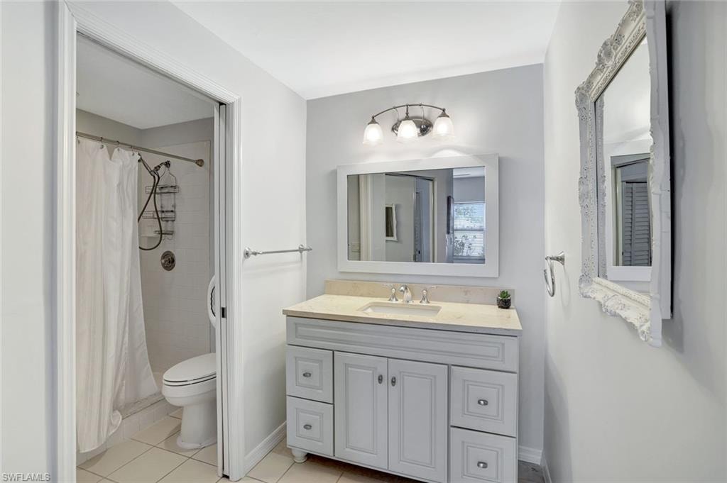 Bathroom featuring vanity, light tile patterned floors, and tiled shower