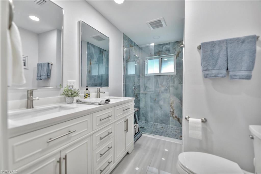 Bathroom with double vanity, a stall shower, and recessed lighting