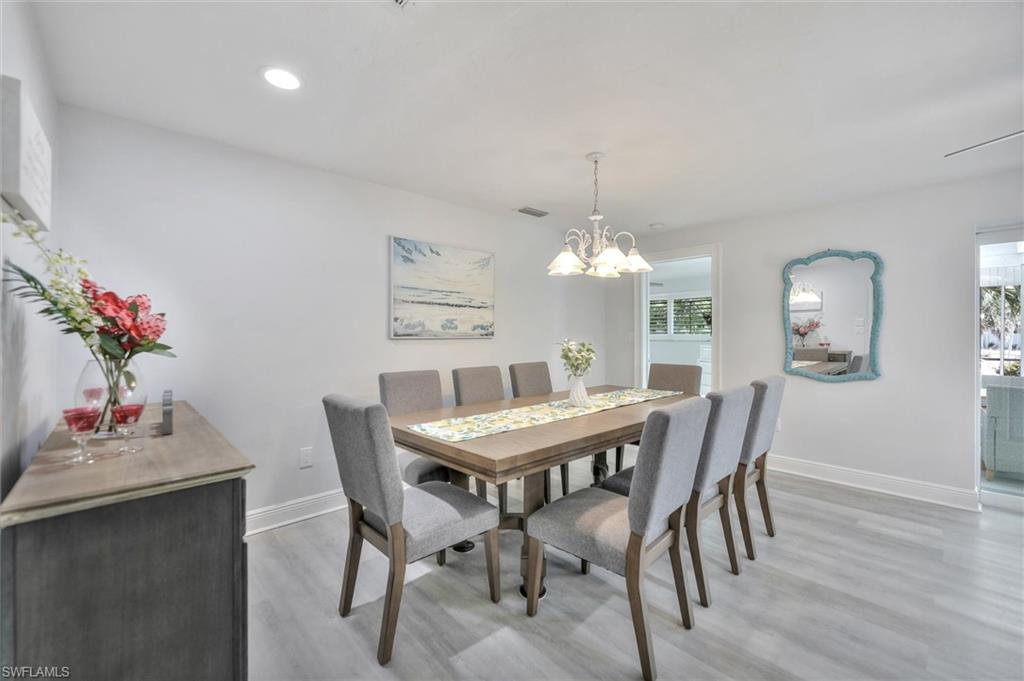 Dining room with light wood finished floors, a chandelier, and recessed lighting