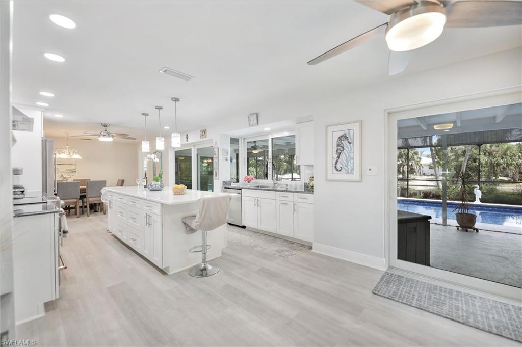 Kitchen featuring ceiling fan, white cabinets, hanging light fixtures, a kitchen island, and recessed lighting