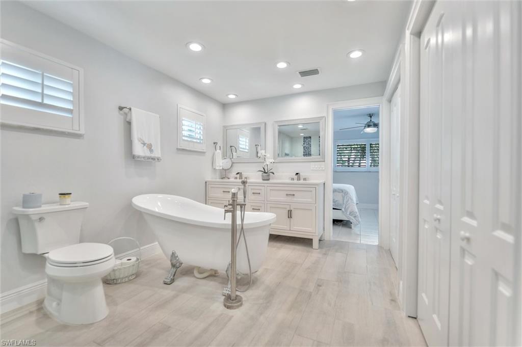 Full bathroom with a freestanding bath, double vanity, recessed lighting, ensuite bath, and light wood-style floors