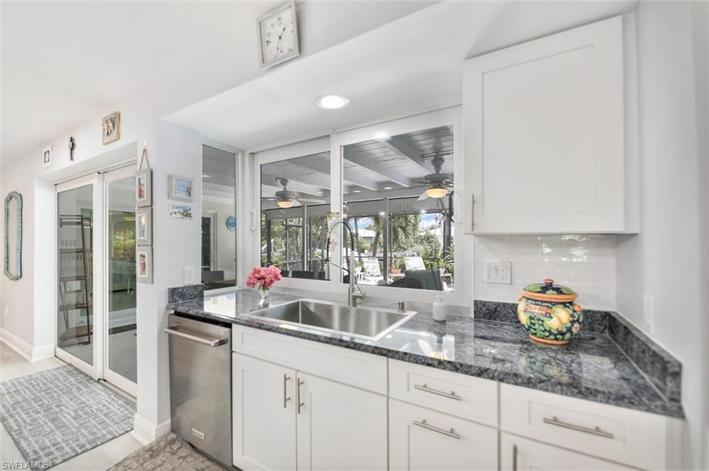 Kitchen featuring white cabinetry, stainless steel dishwasher, recessed lighting, dark stone countertops, and a sunroom