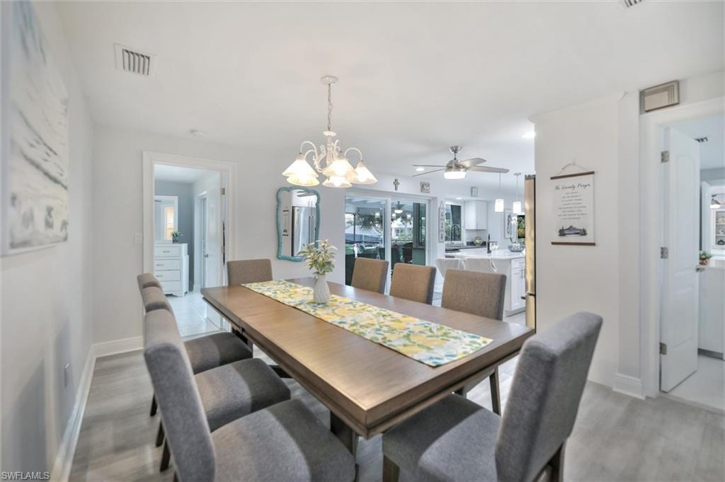 Dining space with a chandelier, ceiling fan, healthy amount of natural light, and light wood-style flooring