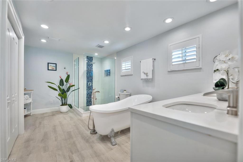 Bathroom with vanity, a shower stall, a soaking tub, recessed lighting, and light wood-type flooring