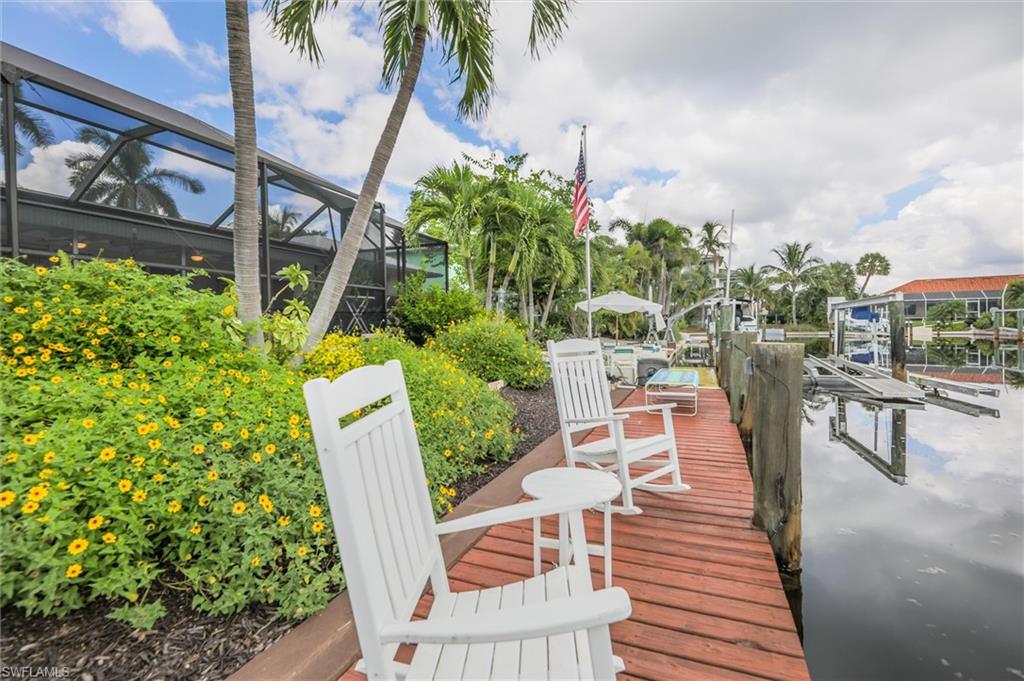 Dock featuring glass enclosure, boat lift, and a water view