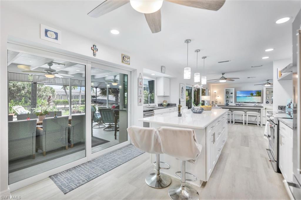 Kitchen with a kitchen breakfast bar, white cabinetry, light wood-style floors, a ceiling fan, and recessed lighting