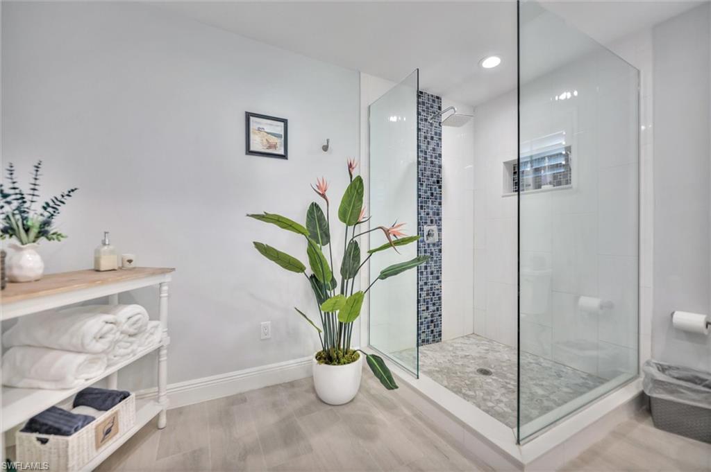 Bathroom featuring a walk in shower, wood finished floors, and recessed lighting