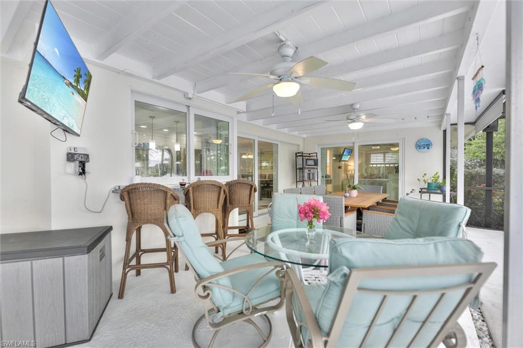 Sunroom featuring outdoor dining space, beam ceiling, a patio area, and ceiling fan