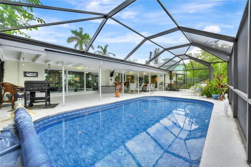 Swimming pool with a lanai, a patio, area for grilling, a sunroom, and ceiling fan