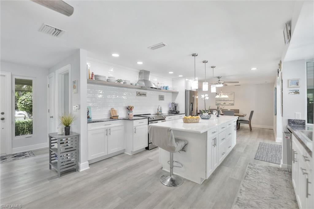 Kitchen with white cabinets, decorative backsplash, stainless steel appliances, pendant lighting, and recessed lighting