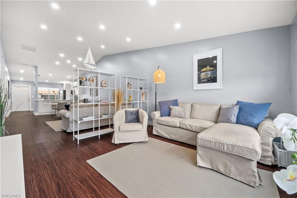 Living room with recessed lighting, dark wood finished floors, and vaulted ceiling