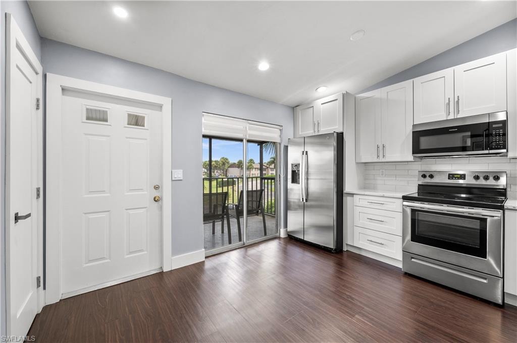 Kitchen featuring appliances with stainless steel finishes, white cabinetry, tasteful backsplash, dark wood-style flooring, and recessed lighting