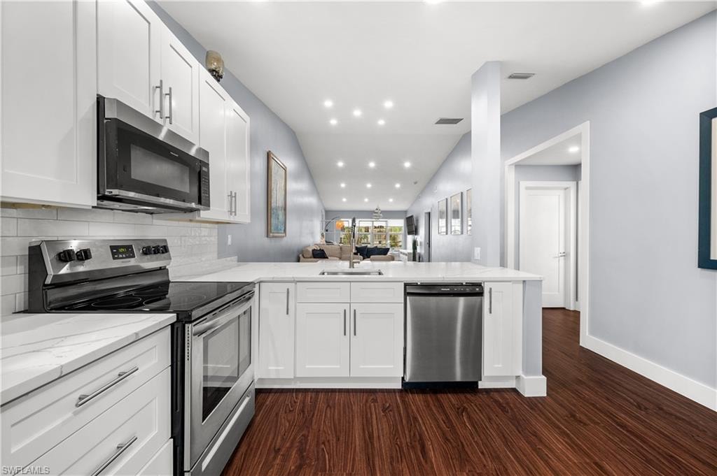 Kitchen with open floor plan, stainless steel appliances, recessed lighting, white cabinets, and a peninsula