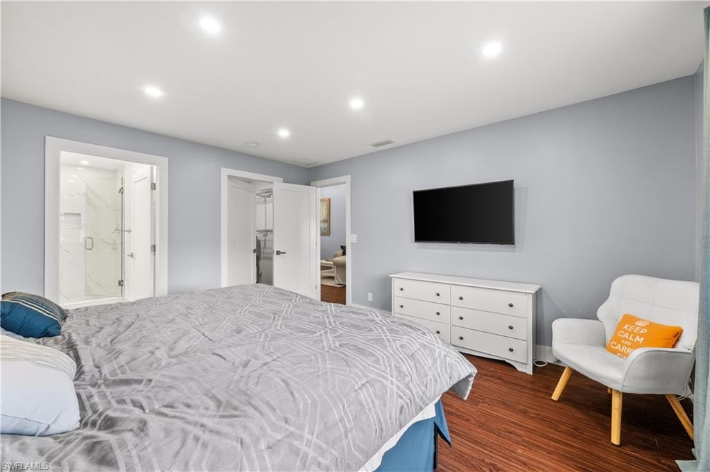 Bedroom with dark wood finished floors, recessed lighting, a spacious closet, and ensuite bathroom