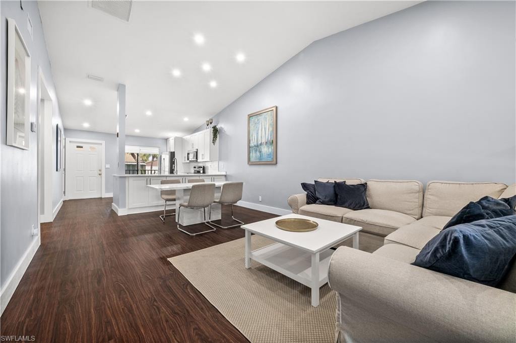 Living area with lofted ceiling, dark wood-type flooring, and recessed lighting