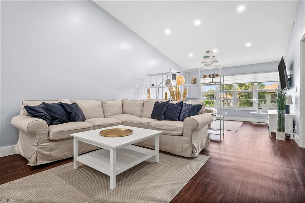 Living area with dark wood finished floors, recessed lighting, and high vaulted ceiling