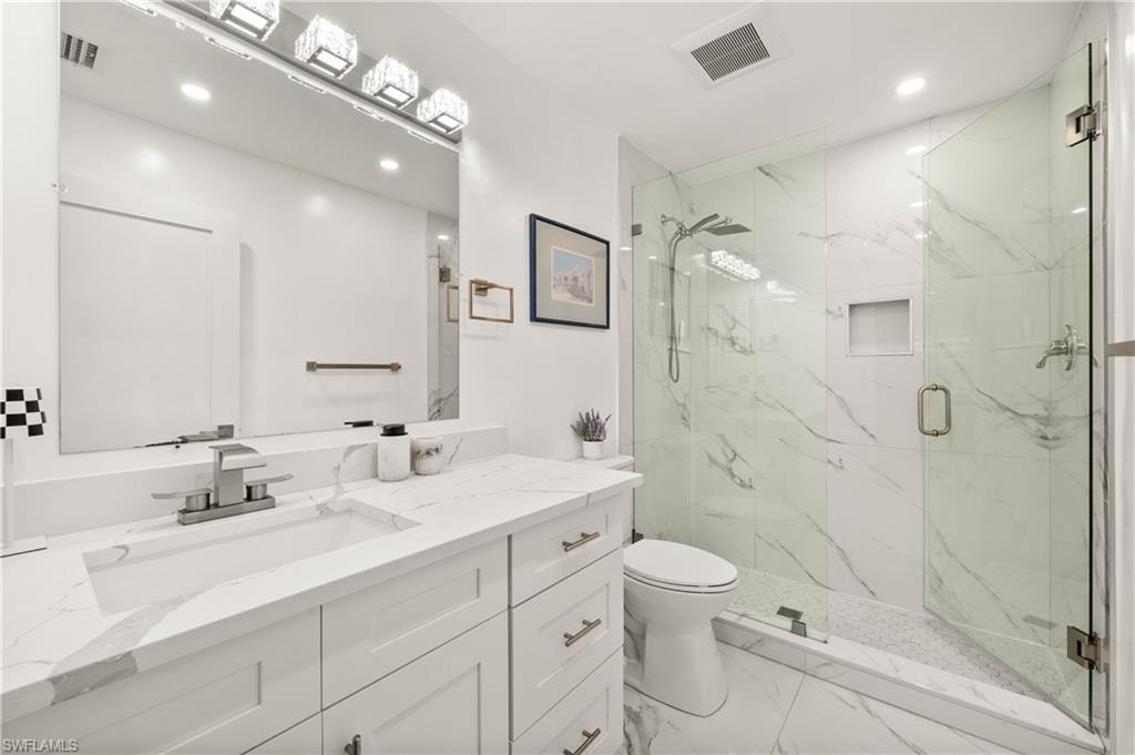 Full bathroom featuring a marble finish shower, vanity, light marble finish flooring, and recessed lighting
