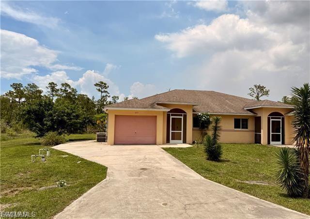 View of front facade with stucco siding, driveway, a garage, and a front yard