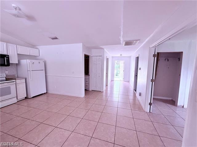 Kitchen featuring white cabinets, white appliances, light tile patterned flooring, tasteful backsplash, and light countertops