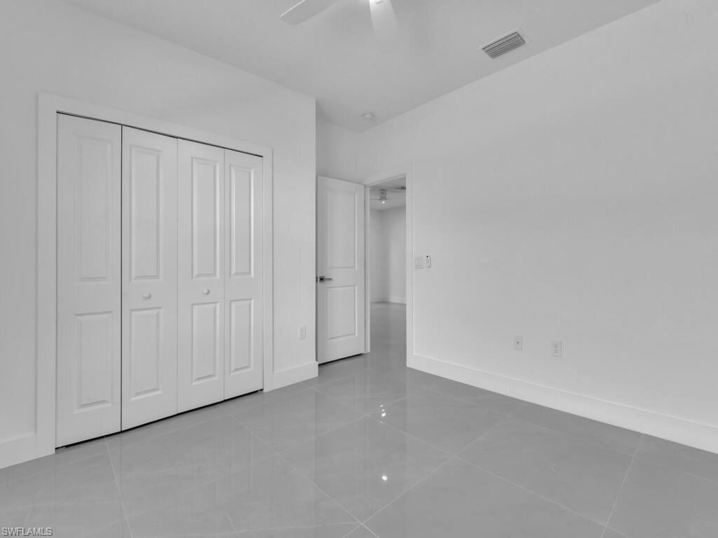 Unfurnished bedroom with light tile patterned floors, a ceiling fan, and a closet