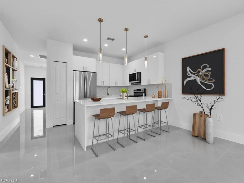 Kitchen featuring a breakfast bar area, white cabinets, a peninsula, modern cabinets, and hanging light fixtures