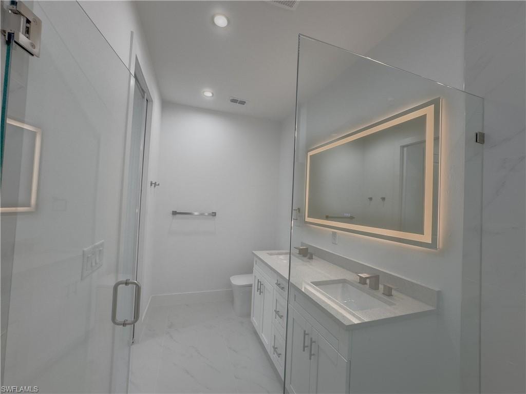 Full bathroom featuring double vanity, recessed lighting, light marble finish flooring, and a marble finish shower
