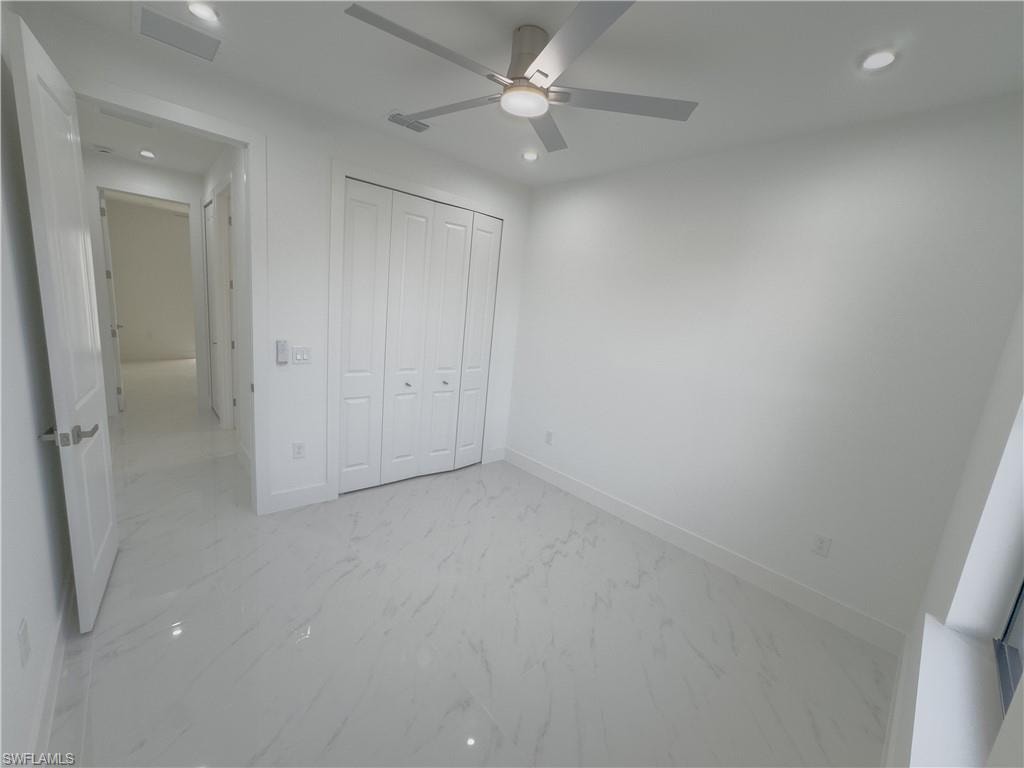 Unfurnished bedroom with recessed lighting, light marble finish flooring, a closet, and a ceiling fan