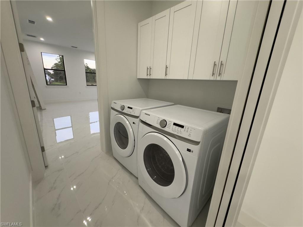 Washroom featuring light marble finish flooring, cabinet space, separate washer and dryer, and recessed lighting
