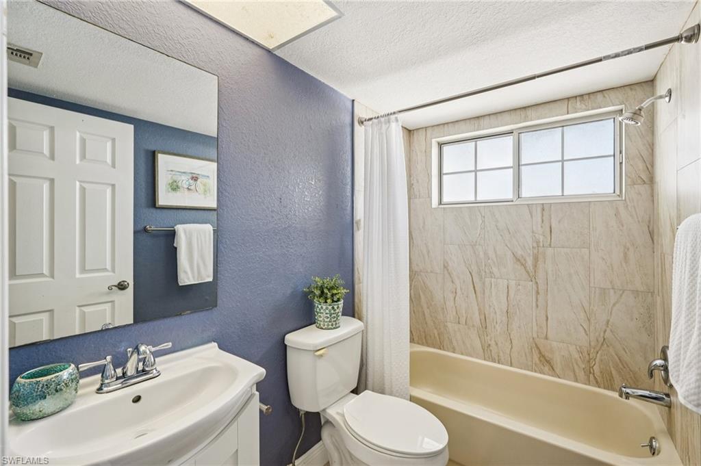 Full bath with a textured wall, shower / tub combo, a textured ceiling, and vanity