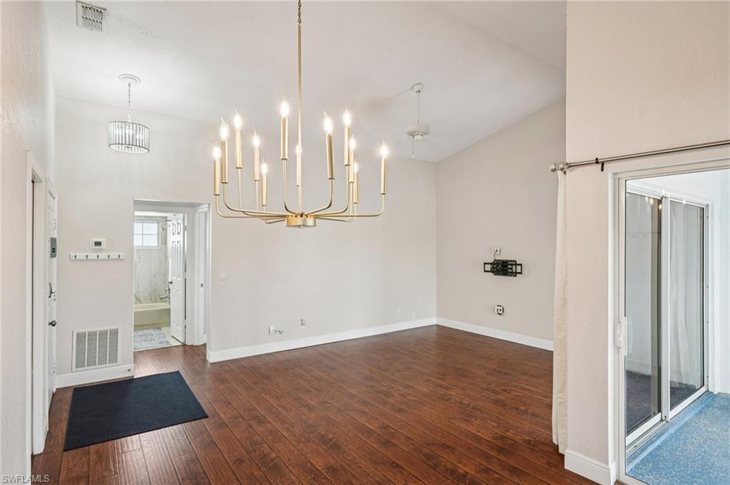 Unfurnished dining area featuring a chandelier, dark wood-style flooring, and a towering ceiling
