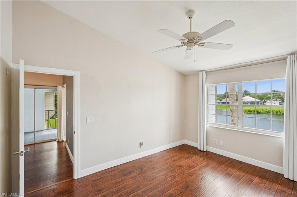Empty room with healthy amount of natural light, dark wood-type flooring, ceiling fan, and lofted ceiling