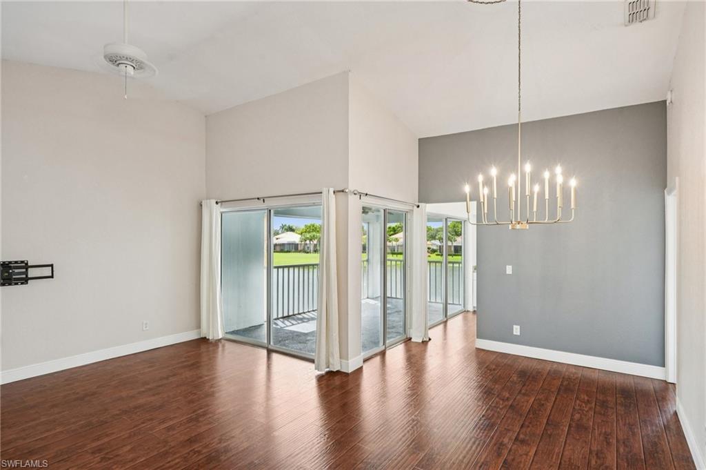 Unfurnished dining area with a chandelier, dark wood-type flooring, a water view, and a high ceiling