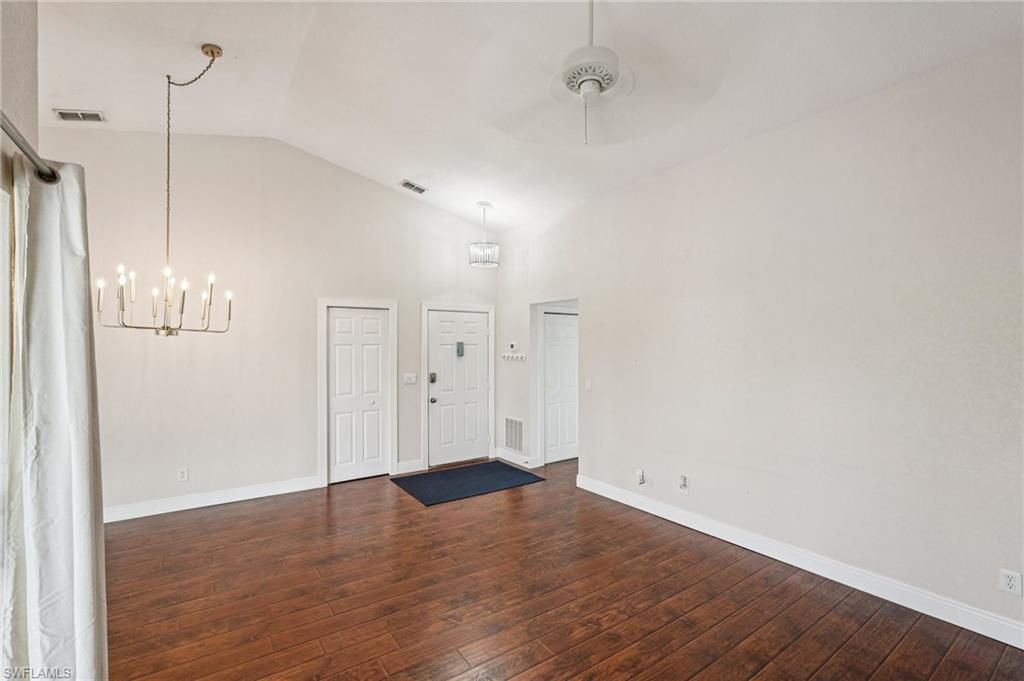 Entrance foyer featuring dark wood-type flooring, high vaulted ceiling, a chandelier, and a ceiling fan