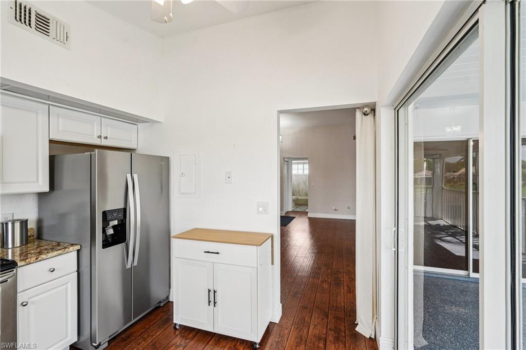 Kitchen with white cabinetry, appliances with stainless steel finishes, dark wood-type flooring, and a towering ceiling
