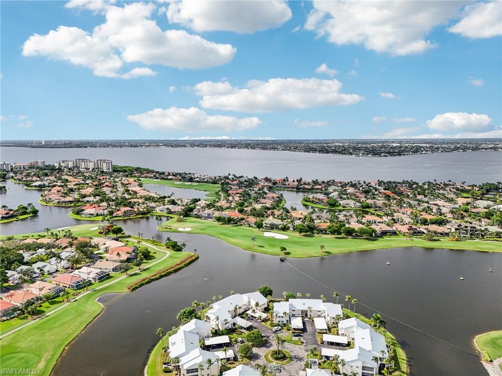 Aerial view of residential area featuring a golf club and a nearby body of water