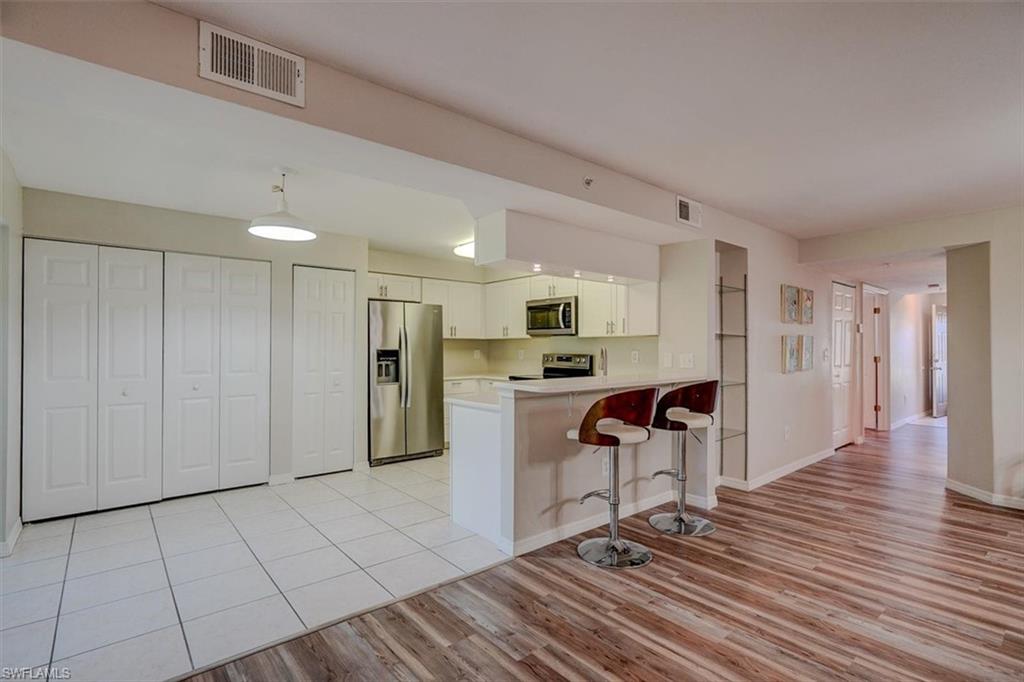 Kitchen with light countertops, stainless steel appliances, a breakfast bar, light wood finished floors, and a peninsula