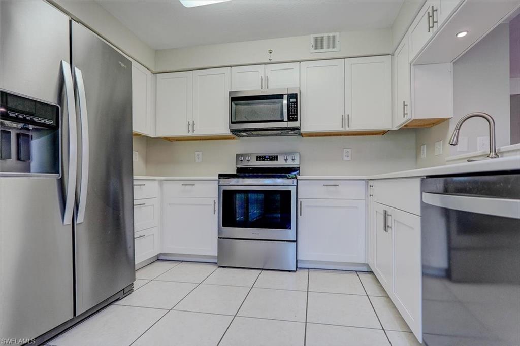 Kitchen with stainless steel appliances, white cabinets, and light tile patterned flooring