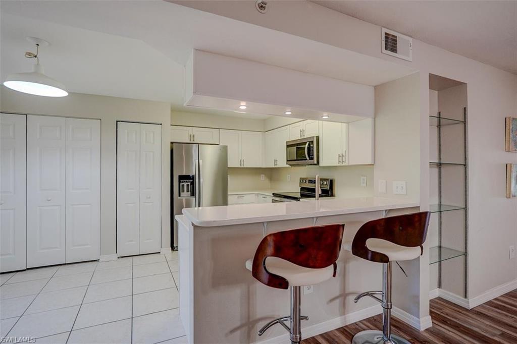 Kitchen with light countertops, a breakfast bar, appliances with stainless steel finishes, a peninsula, and white cabinetry